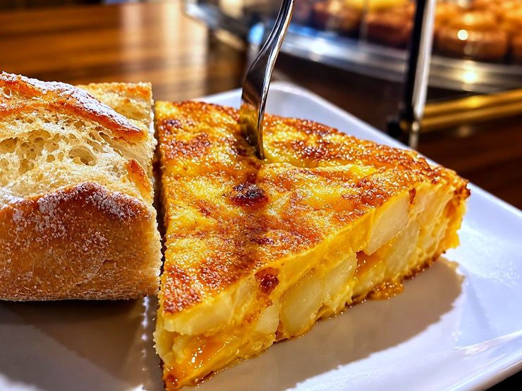 Un pincho de tortilla de patata recién hecha, al corte, con un trozo de pan, en el bar La Plaza