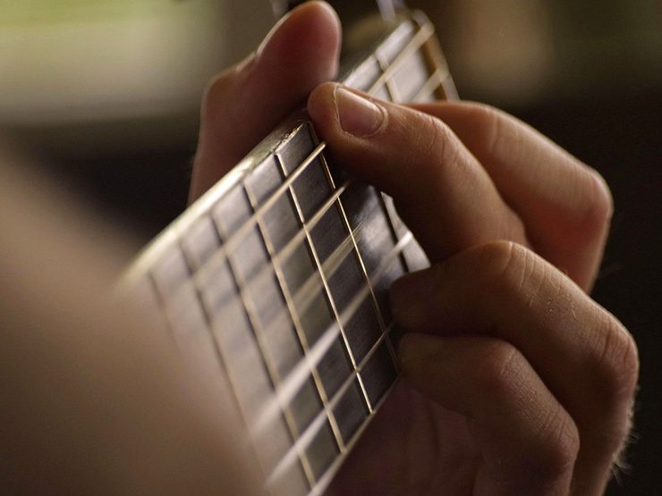Manos tocando la guitarra en directo en el bar La Plaza